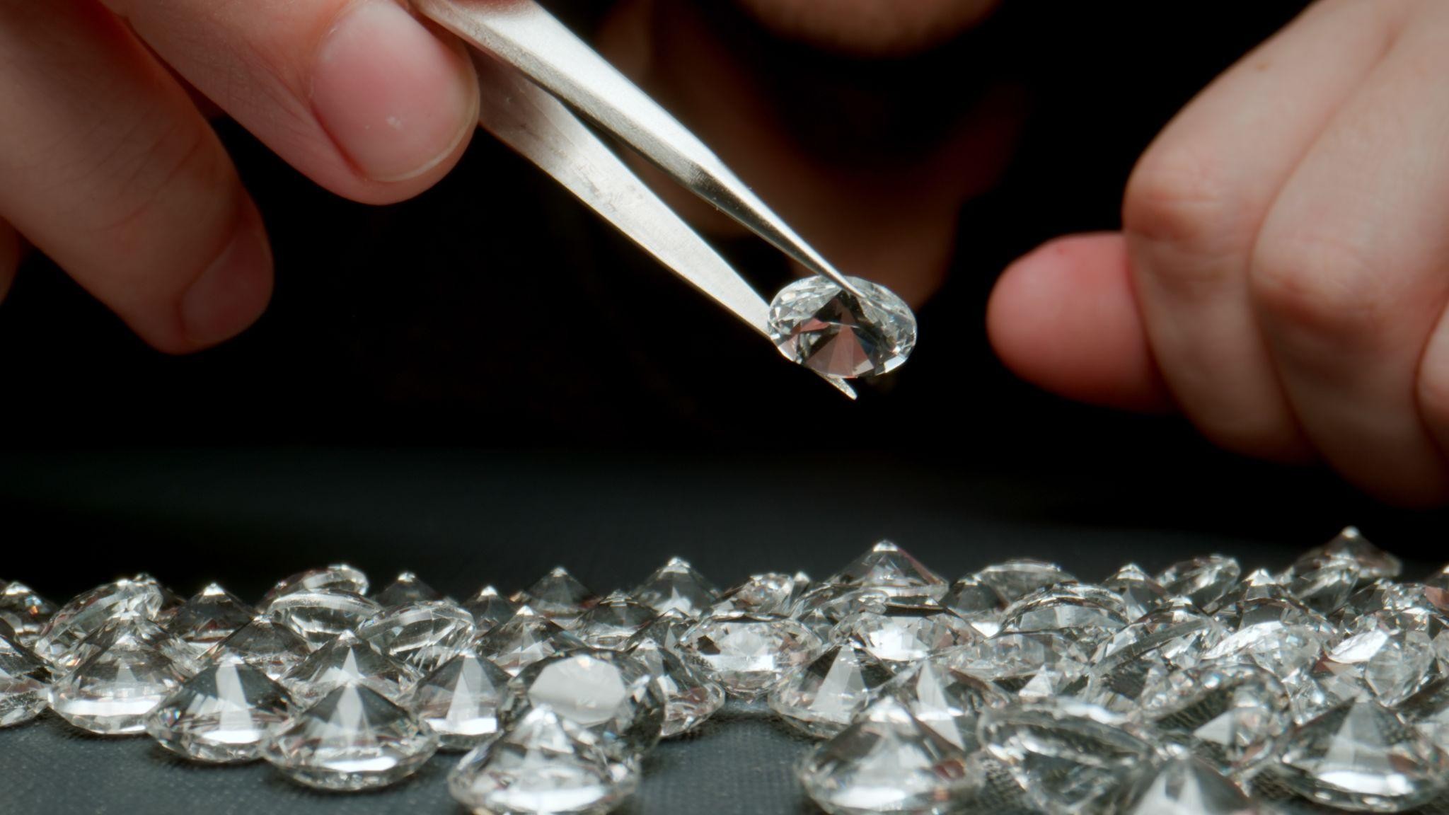 Loose diamonds being examined with jeweler tweezers