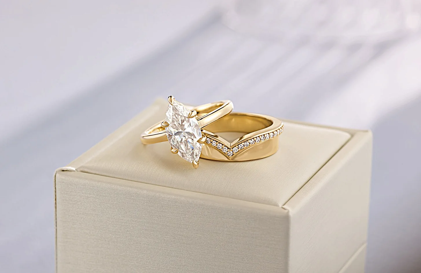 Marquise solitaire engagement ring in yellow gold paired with a contoured chevron diamond wedding band